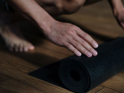 Rolled up yoga mat on dark floor.